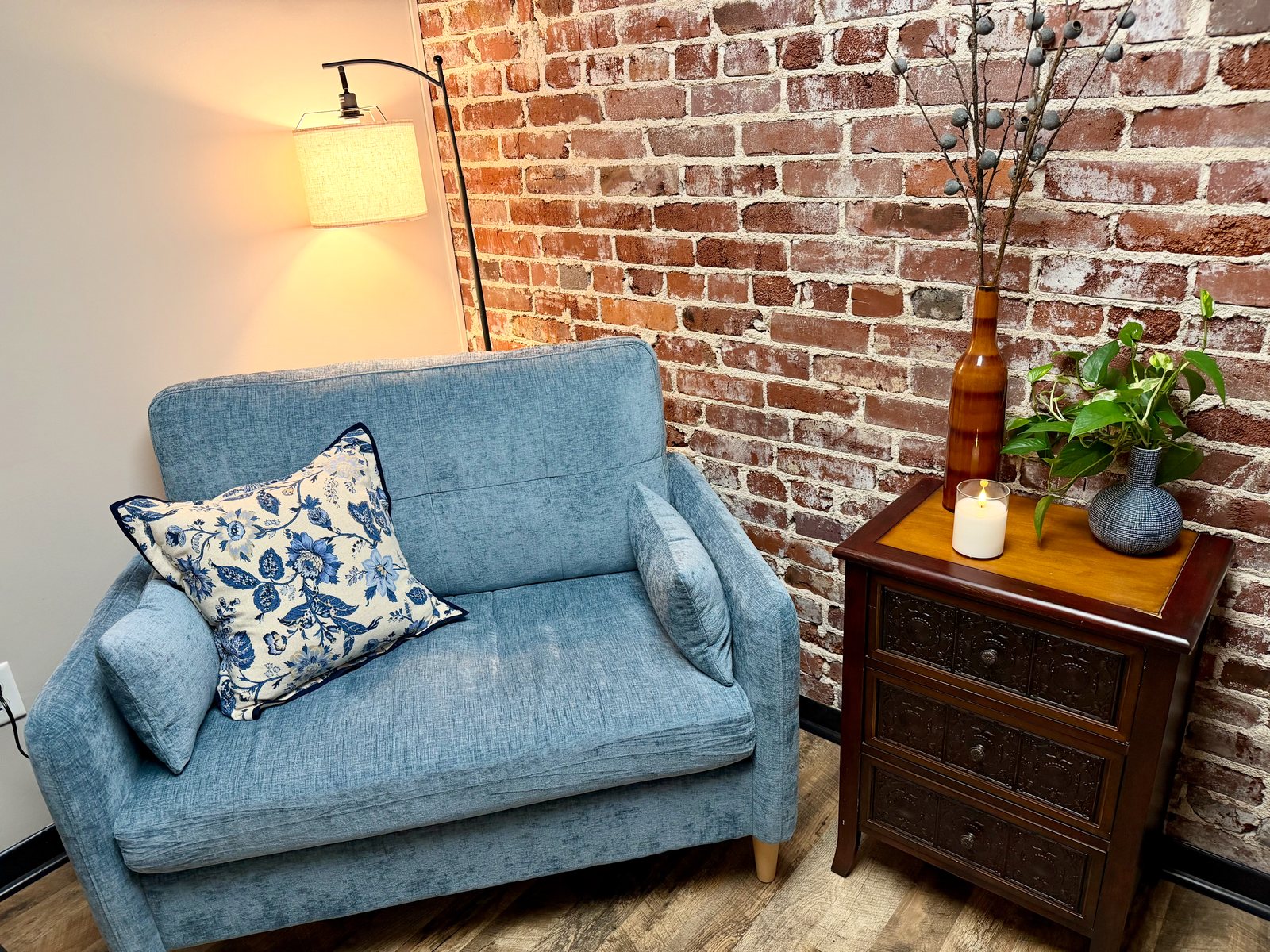 The therapy office: a blue loveseat against an exposed brick wall